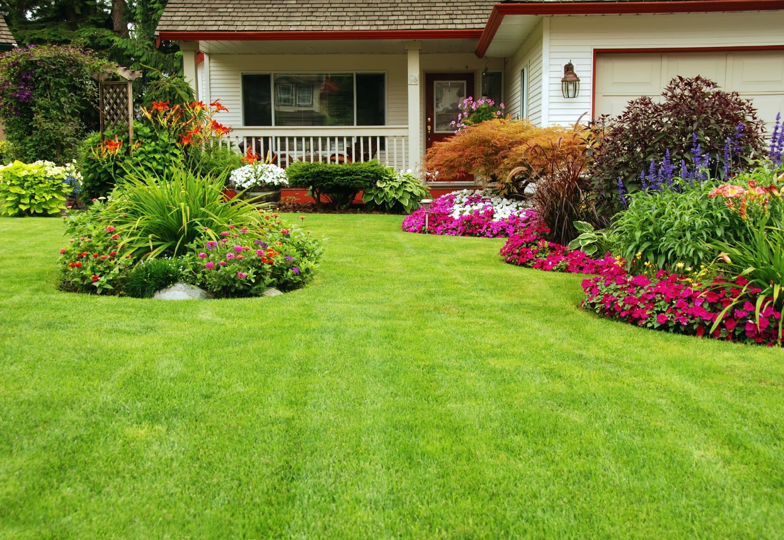 Exterior of a suburban home with a healthy green lawn and manicured flower beds in bloom.