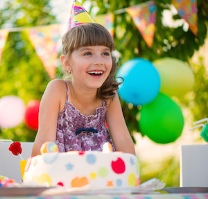 Little girl with a birthday cake at a birthday party